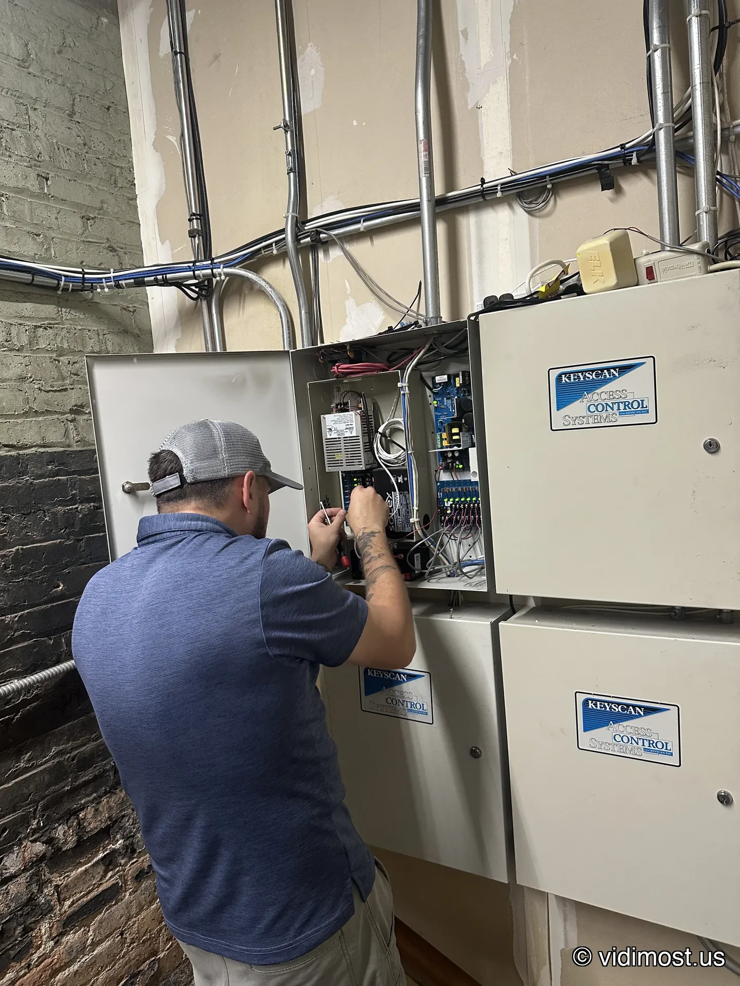 Technician servicing a legacy Keyscan access control panel enclosure in a Chicago building